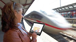 Lächelnde Dame am Bahnhof mit ihrem Ipad